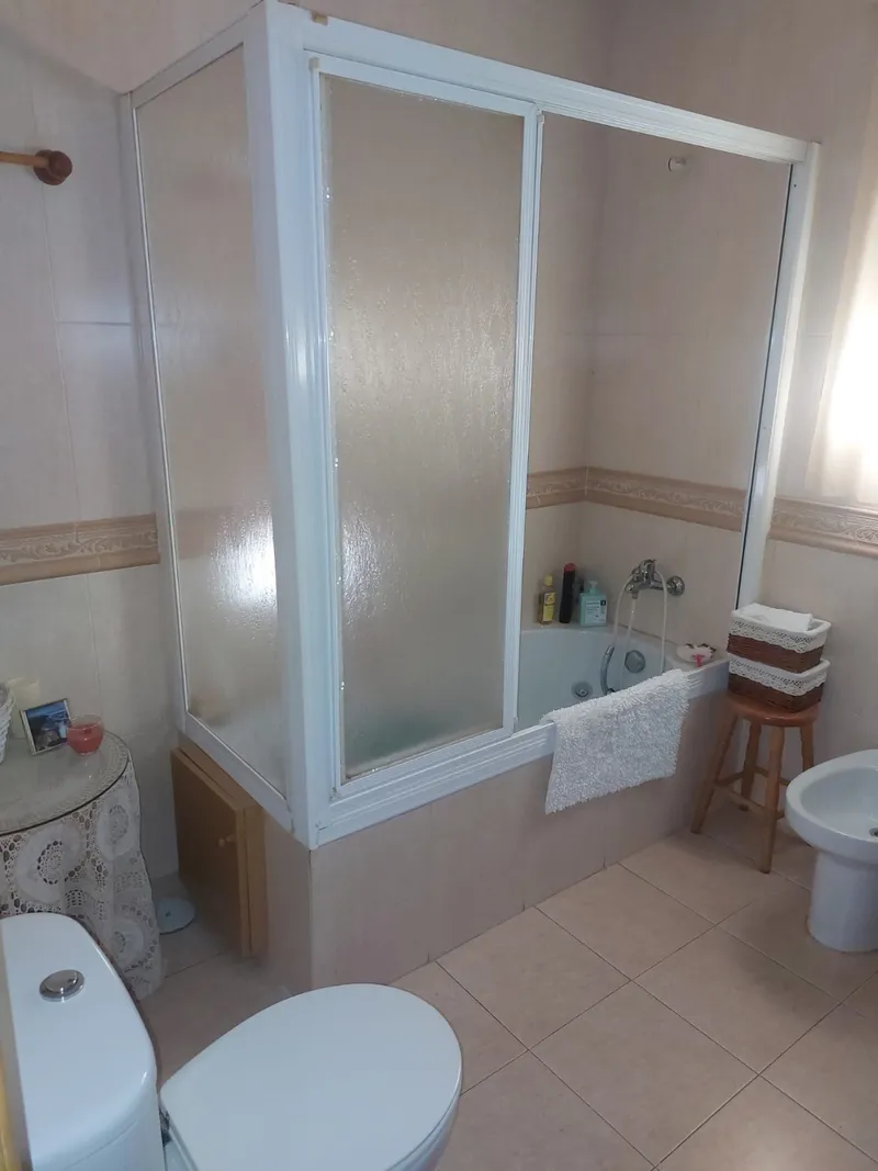 Baño con bañera alta y mampara opaca, antes de la reforma