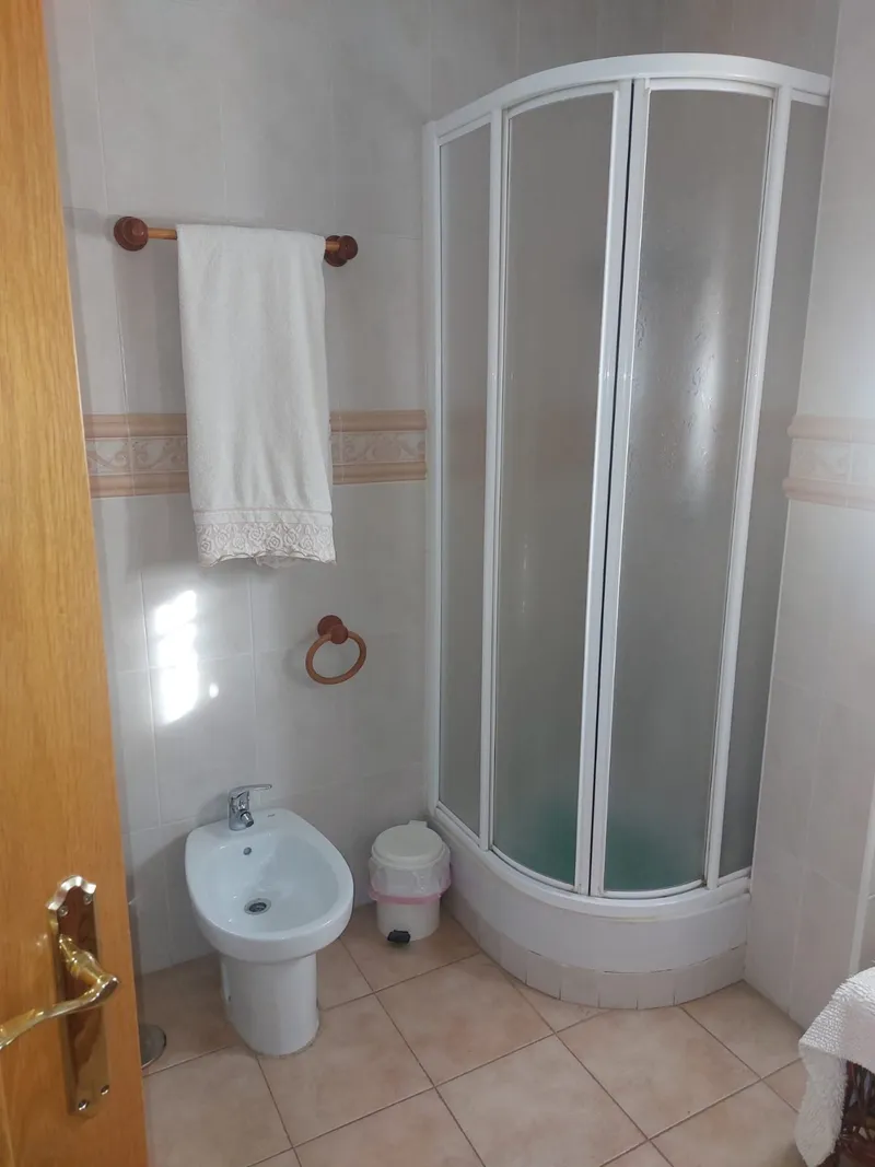 Baño con ducha curva y distribución que penalizaba la zona de paso, antes de la reforma