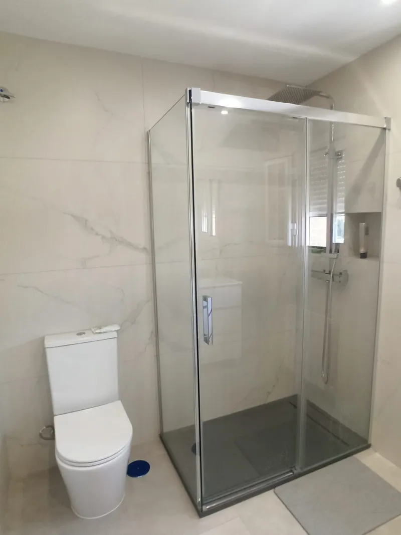 Baño con mampara rectangular de cristal transparente y plato de ducha texturizado antracita, después de la reforma