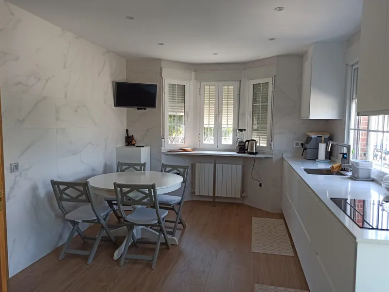 Cocina con suelo porcelánico imitación madera y revestimiento imitación mármol, después de la reforma